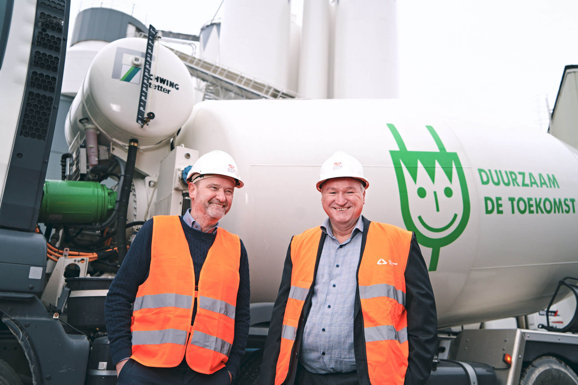 two men in high vis vest and hardhats, walking and talking